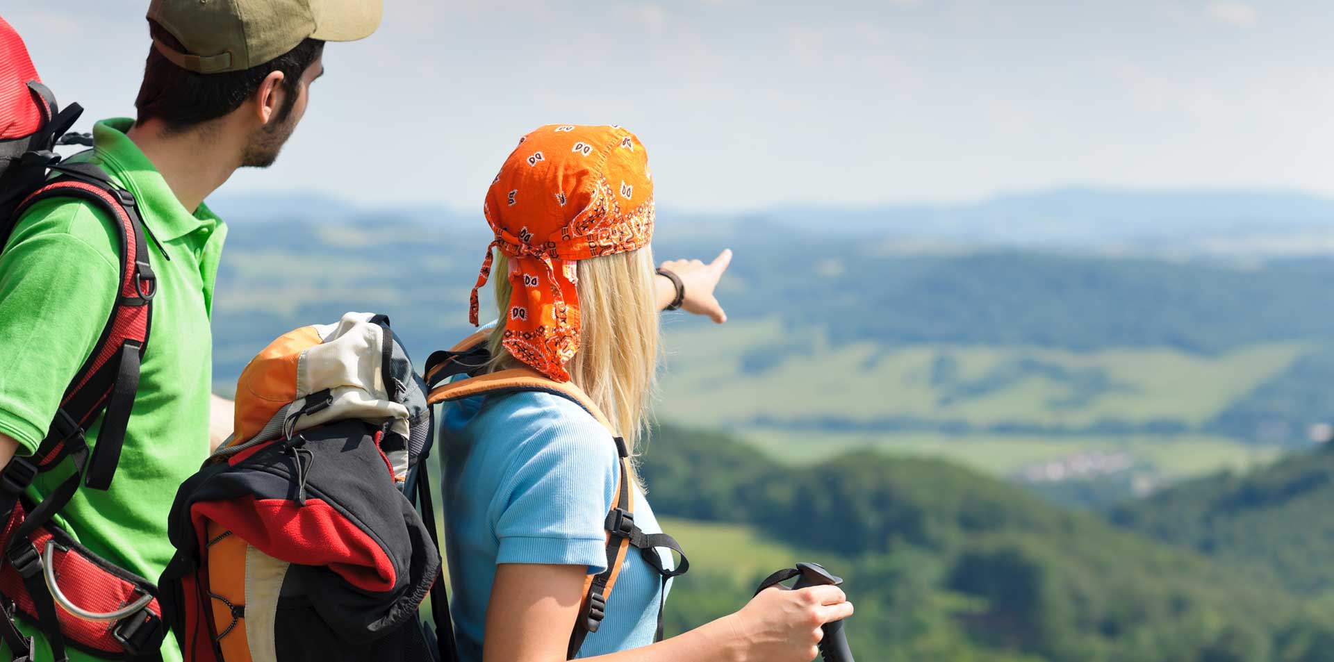 Female and Male Backpackers With Backpacks On Their Backs Looking And Pointing At Scenery While Living Working Playing and Travelling Around The World.
