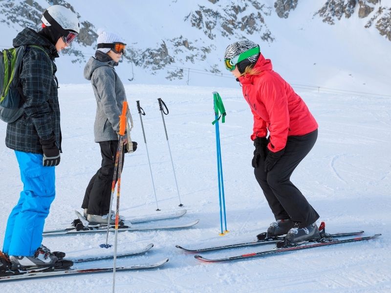 Ski Instructor With Two Students Learning To Ski In The Snow.