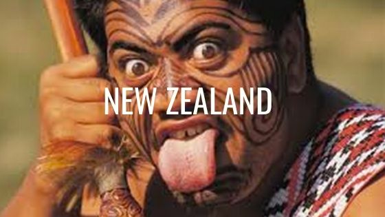 Maori With A Tattoos On His Face And His Tongue Poking Out With The Words New Zealand.