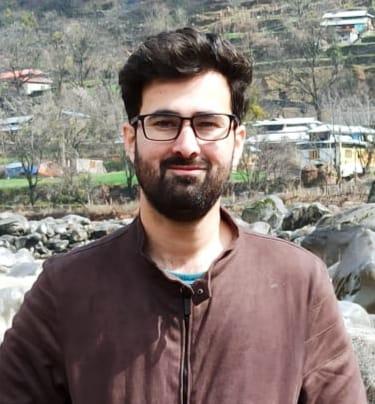 Syed Asad. Man With Dark Hair And A Beard Smiling.