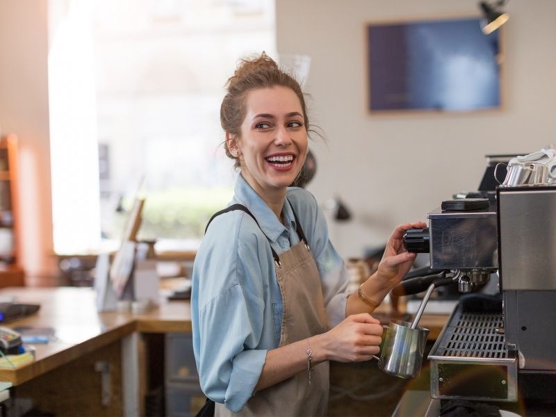 Female Making Coffee At A coffee Machine In A Coffee Shop. A Barista Job Is A Popular Working Holiday Job.