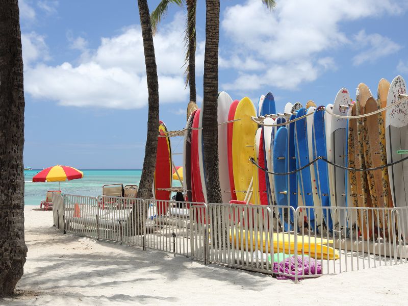 Surfboards Standing Up In Sand At Waikiki Beach Waiting To Be Hired.