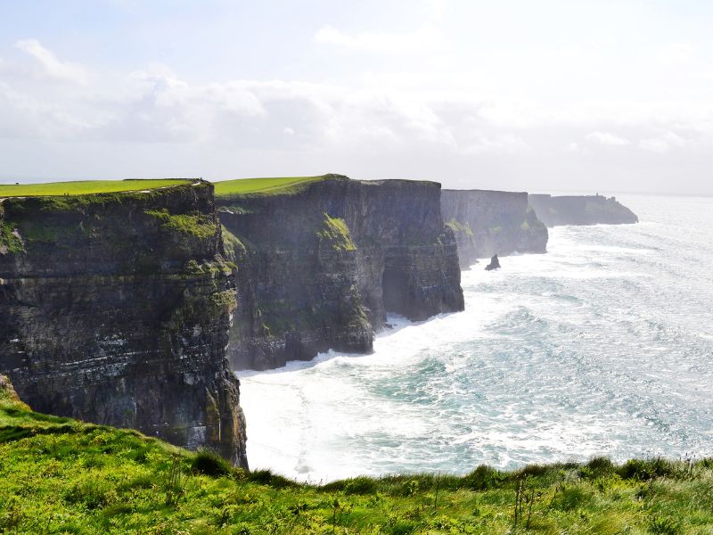 Steep cliffs in Ireland - the Cliffs of Moher with the ocean pounding against them.