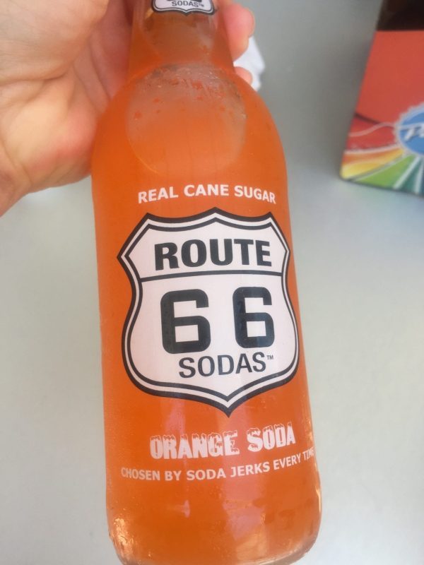 Pops Soda Bottle with orange soda with Route 66 Sign on front of bottle.