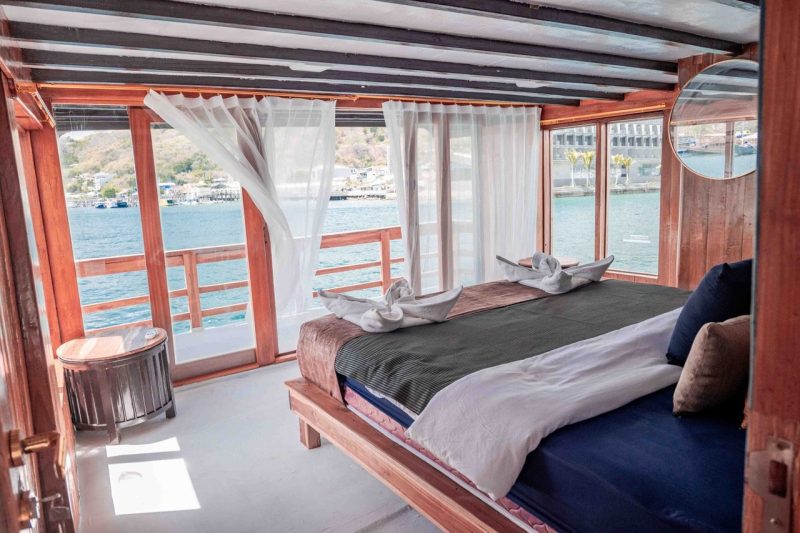 Inside Phinisi Boat Bedroom. Bed With View Over Water.