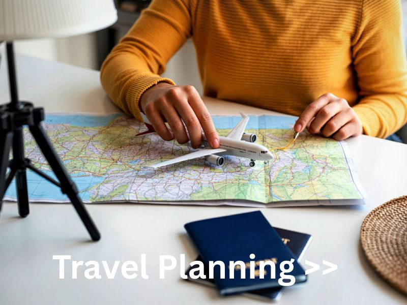 person sitting at table planning their travel with a map