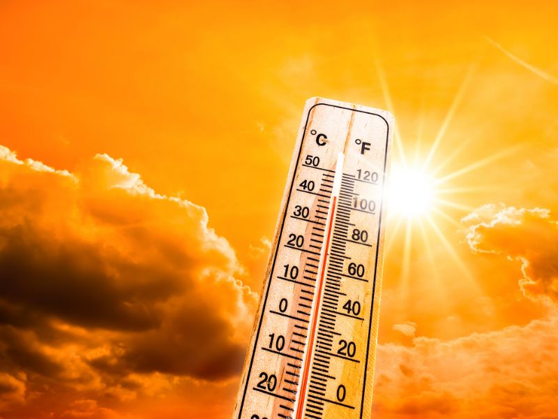 Hot temperature showing heatwave on a thermometer with blazing sun with golden sky behind